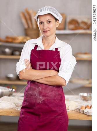 Professional female baker standing with folded arms in bakery 141729077
