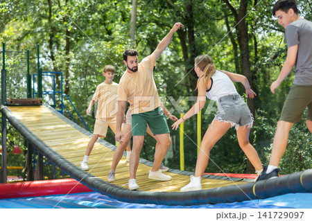 Group trying to cross moving swinging bridge over trampoline Group trying to cross moving swinging bridge over trampoline 141729097