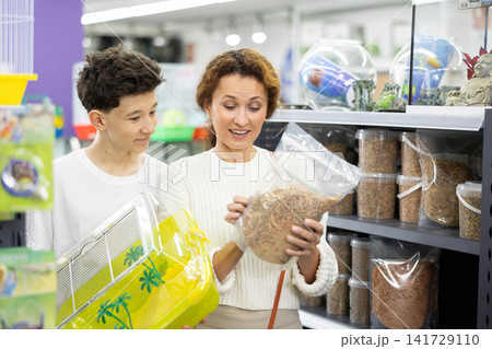 Family mom and son in animal goods store examines packaging of dry food for turtles Family mom and son in animal goods store examines packaging of dry food for turtles 141729110