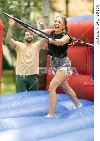 Young girl having funny competition in collect of hoops on inflatable trampoline in summer outdoor amusement park Young girl having funny competition in collect of hoops on inflatable trampoline in summer outdoor amusement park 141729186