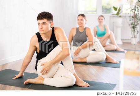 Group of young people doing a spinal twist pose. 141729755