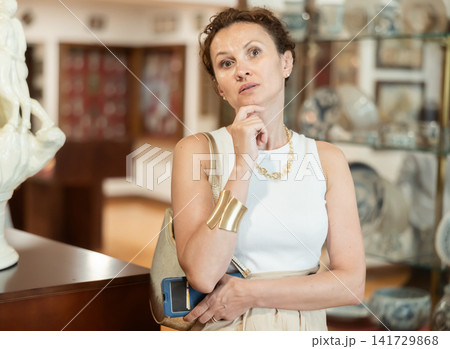 Interested woman examining collection of artifacts in historical museum Interested woman examining collection of artifacts in historical museum 141729868