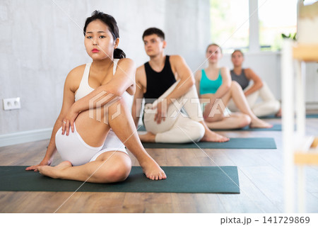 Group of young people doing a spinal twist pose. Group of young people doing a spinal twist pose. 141729869