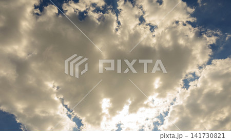 fluffy sunny cloud close up illuminated by bright rays against a clear blue sky background fluffy sunny cloud close up illuminated by bright rays against a clear blue sky background 141730821
