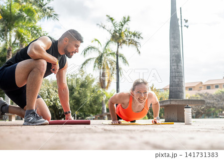 Woman doing push ups with personal trainer 141731383