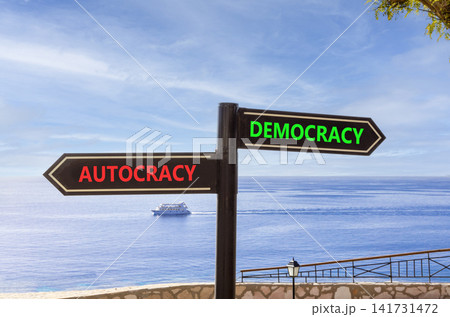 Democracy or autocracy words symbol. Concept words Democracy Autocracy on beautiful black road sign. Beautiful blue sky background. Business democracy autocracy concept. Copy space Democracy or autocracy words symbol. Concept words Democracy Autocracy on beautiful black road sign. Beautiful blue sky background. Business democracy autocracy concept. Copy space 141731472