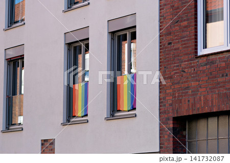 Rainbow pride flags hanging in windows of modern residential building in European city Rainbow pride flags hanging in windows of modern residential building in European city 141732087