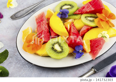 Tropical fruit salad with mango, kiwi, watermelon, orange and edible flowers Tropical fruit salad with mango, kiwi, watermelon, orange and edible flowers 141732303