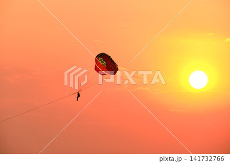 Parasailing at sunset in Jomtien Pattaya Thailand with colorful canopy and orange sky Parasailing at sunset in Jomtien Pattaya Thailand with colorful canopy and orange sky 141732766