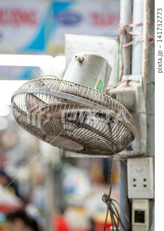 Dirty electric fan clogged and filled with dust, sticking over grille at street market in Asia, Dirty electric fan clogged and filled with dust, sticking over grille at street market in Asia, 141732773