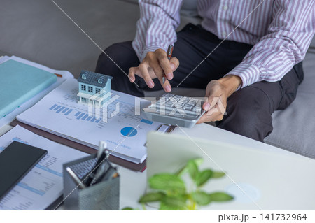 Man using calculator to calculate home budget and mortgage costs. 141732964