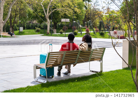 Arfican american couple man and woman tourists relax in city garden enjoying carefree conversation. Arfican american couple man and woman tourists relax in city garden enjoying carefree conversation. 141732965