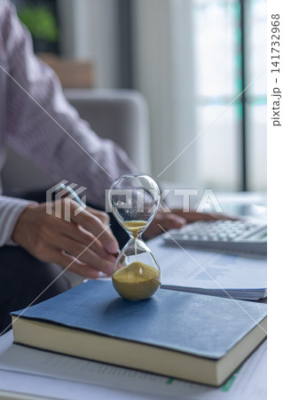 Business Consultant Analyzing Data Sheets and Financial Charts at Desk with Hourglass on Table. Time Management Concept. 141732968