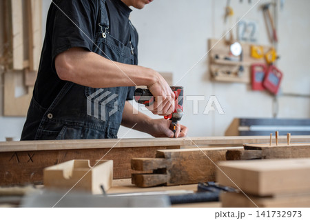 Craftsman technician working in restoration workshop, using professional cordless impact driver tool 141732973