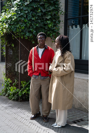 Relaxed african american couple man and woman students meeting outdoors after lessons for chat. Relaxed african american couple man and woman students meeting outdoors after lessons for chat. 141732974