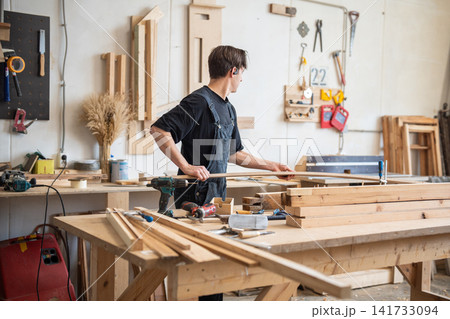 Busy workday at restoration workshop, craftsman working with wooden materials for frame repair. 141733094