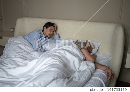 Angry tired senior woman with insomnia and fatigue struggling to sleep beside loudly snoring husband Angry tired senior woman with insomnia and fatigue struggling to sleep beside loudly snoring husband 141733150