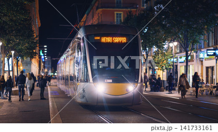 Nice, France - November 2, 2018 - Tram at night on Massena square with pedestrians Nice, France - November 2, 2018 - Tram at night on Massena square with pedestrians 141733161