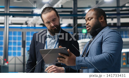 Group of industry experts analyzing solar panel systems during a production inspection, ensuring engineering accuracy, quality control and factory operations efficiency. Sustainability. Camera B. Group of industry experts analyzing solar panel systems during a production inspection, ensuring engineering accuracy, quality control and factory operations efficiency. Sustainability. Camera B. 141733431