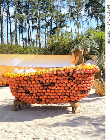 An original art sculpture of a bathtub made of orange pumpkins on the sandy beach. An original art sculpture of a bathtub made of orange pumpkins on the sandy beach. 141733594