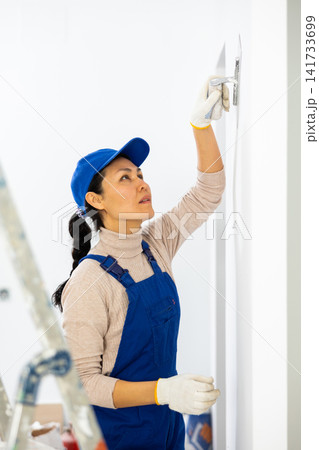 Portrait of professional female builder in process of repair at house Portrait of professional female builder in process of repair at house 141733699