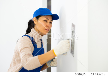 Portrait of female builder in process of finishing work in cottage Portrait of female builder in process of finishing work in cottage 141733755