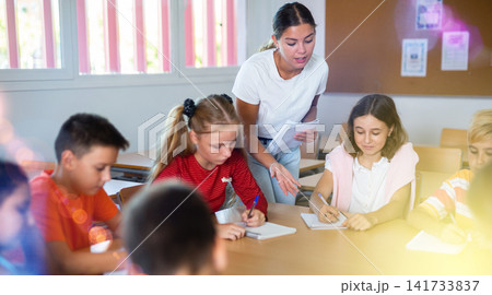 Kids sitting around desk in classroom and studying during lesson 141733837