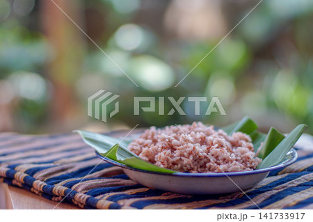 Traditional Indonesian brown rice served on banana leaf plate with natural lighting. Healthy Asian food, whole grain rice, authentic Southeast Asian cuisine. Traditional Indonesian brown rice served on banana leaf plate with natural lighting. Healthy Asian food, whole grain rice, authentic Southeast Asian cuisine. 141733917
