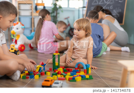 Older boy and younger girl playing with blocks in kindergarten room Older boy and younger girl playing with blocks in kindergarten room 141734078