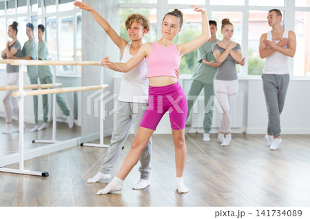 Ballet studio - teenagers girls and boys learn ballet movements in pairs 141734089