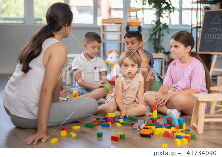 Children of different ages playing with wooden blocks with teacher Children of different ages playing with wooden blocks with teacher 141734090