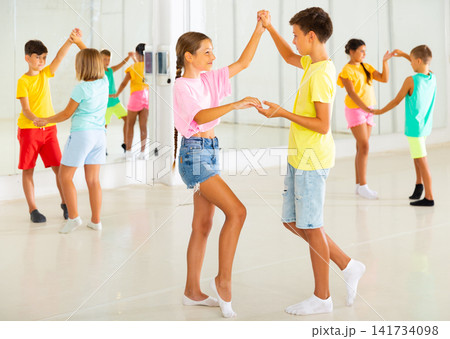 Sporty preteen children learning to dance vigorous jive in pairs Sporty preteen children learning to dance vigorous jive in pairs 141734098