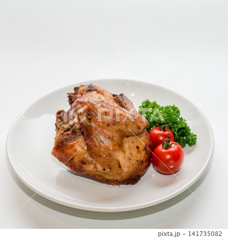 Roasted chicken breast quarter served on white plate with parsley and cherry tomato. 141735082
