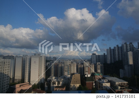 Urban apartment complex under a blue sky and fluffy white clouds Urban apartment complex under a blue sky and fluffy white clouds 141735101