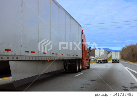 Several trucks drive along USA highway surrounded by mountains in North Carolina travelers distance. Several trucks drive along USA highway surrounded by mountains in North Carolina travelers distance. 141735483