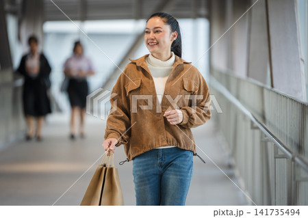 happy woman with shopping bag walking on footbridge in city 141735494