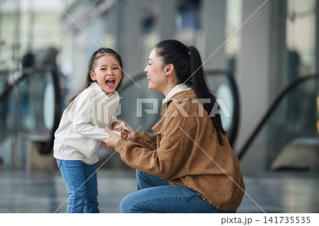 excited child girl laughing with her mother in shopping mall or department store excited child girl laughing with her mother in shopping mall or department store 141735535