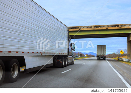 Two trucks drive on highway under an overpass as day begins in South Carolina area. Two trucks drive on highway under an overpass as day begins in South Carolina area. 141735925