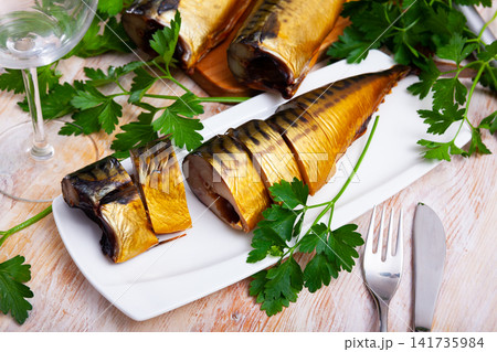 Image of sliced smoked mackerel fish served with greens 141735984
