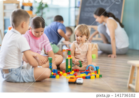 Little children sitting on floor together and playing educational games and toys at classes for kids 141736102