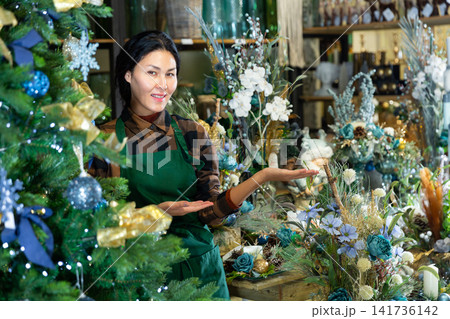 Woman salesman decorates christmas tree in flower shop 141736142