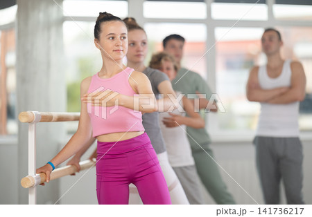 Girl during group class perform third position under male teacher guidance. Girl during group class perform third position under male teacher guidance. 141736217