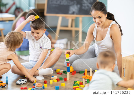 Children of different ages playing with wooden blocks with teacher Children of different ages playing with wooden blocks with teacher 141736223