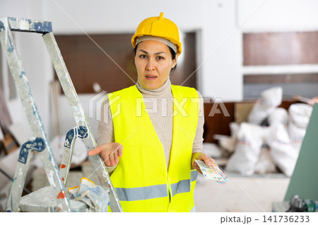 Female repairer holding cash and dissapointed by her wage Female repairer holding cash and dissapointed by her wage 141736233