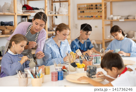 Children sit at the table and paint ceramics Children sit at the table and paint ceramics 141736246