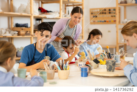 Teenage boy looking at a group mate while working with ceramica 141736292