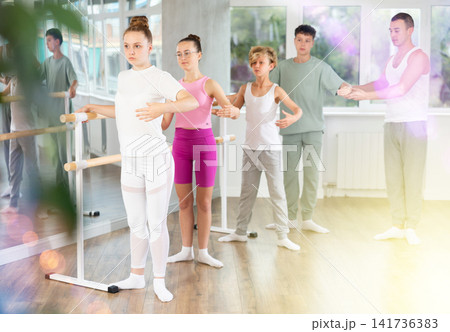 Teenage boys and girls practicing first position of ballet in dancehall 141736383