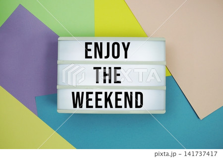 Enjoy the Weekend text in lightbox flat lay on colorful pastel background Enjoy the Weekend text in lightbox flat lay on colorful pastel background 141737417
