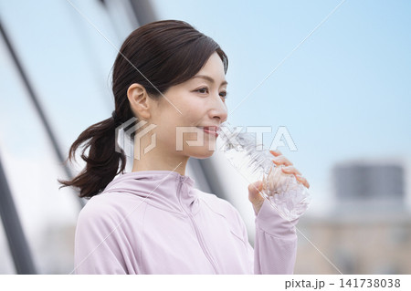 ウォーキング中にペットボトルの水を飲むミドル女性 ウォーキング中にペットボトルの水を飲むミドル女性 141738038