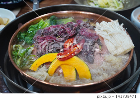 Sliced beef Bulgogi hot pot boiling on a traditional bronze pan with vegetables Sliced beef Bulgogi hot pot boiling on a traditional bronze pan with vegetables 141738471